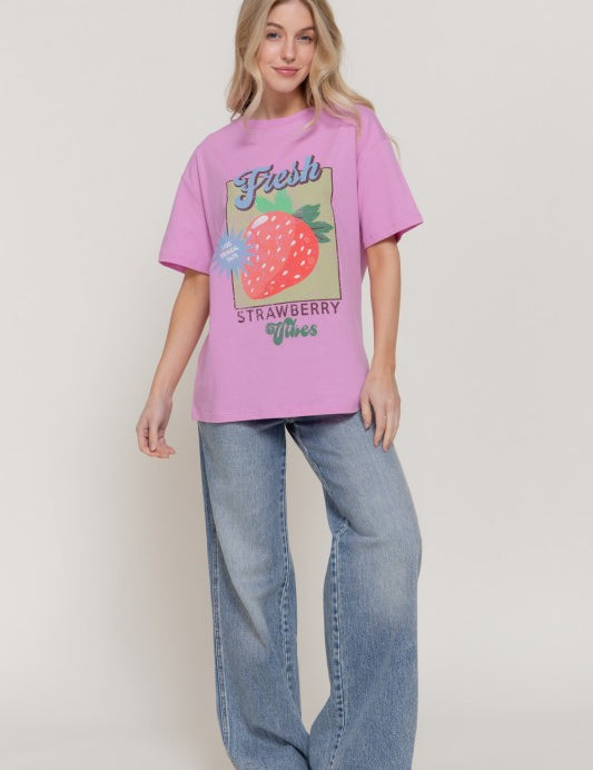 Model wearing a Sweet Patch Graphic Tee, featuring a graphic of a strawberry, styled with wide-leg jeans.