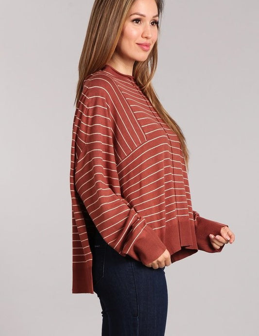 Model wearing the Aubrey Knit Pullover, a striped oversized top with mock neck and side slits, styled with denim.