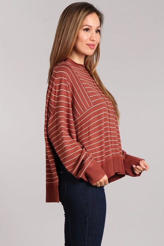 Model wearing the Aubrey Knit Pullover, a striped oversized top with mock neck and side slits, styled with denim.